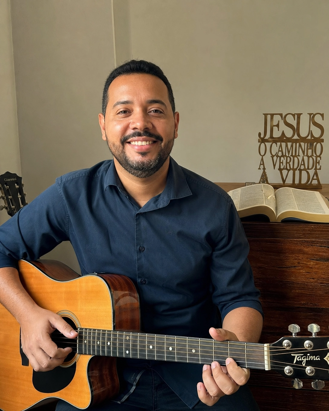 Marcos Oliveira, professor de violão gospel, sorrindo com violão nas mãos